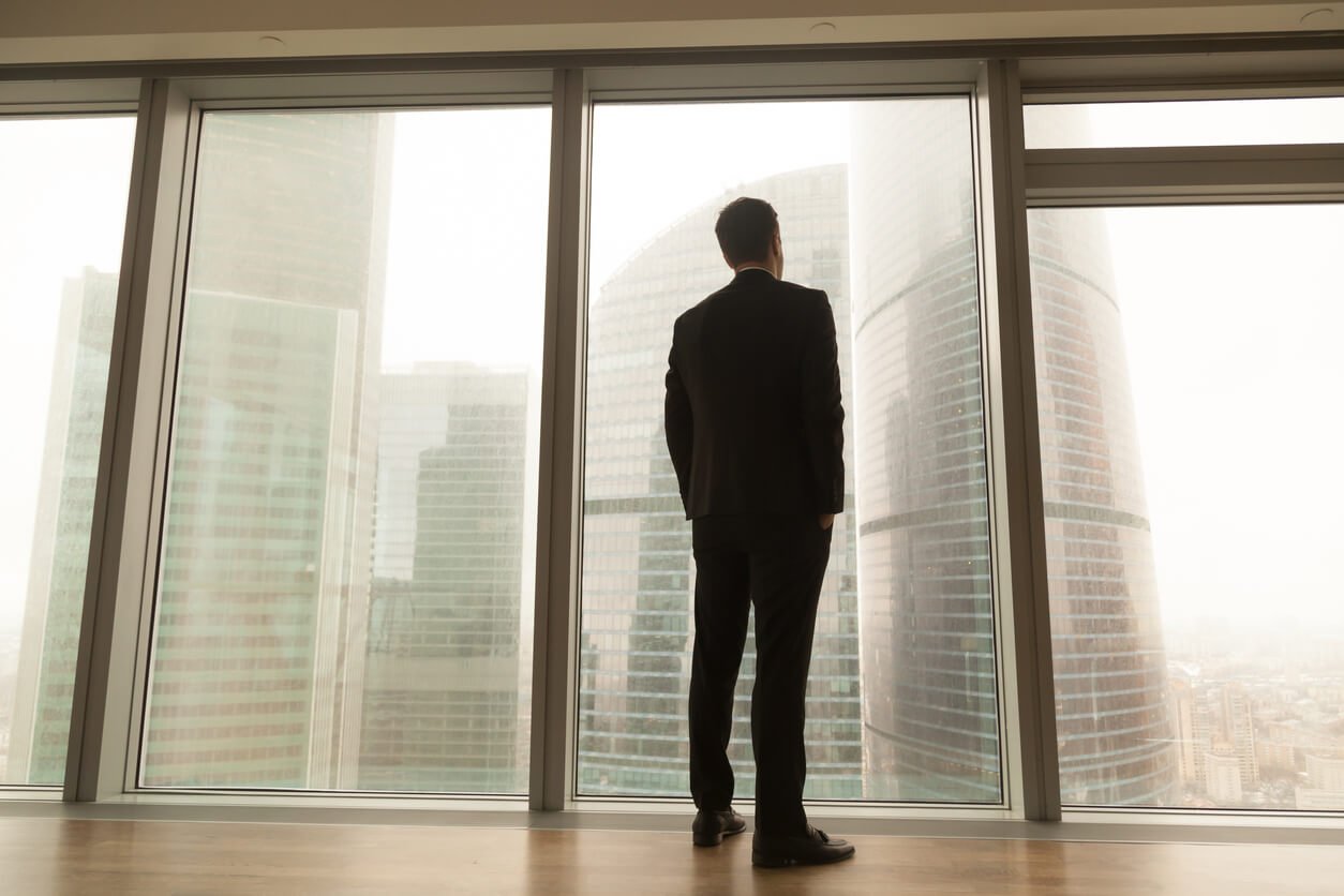 business man looking out of window onto cityscape