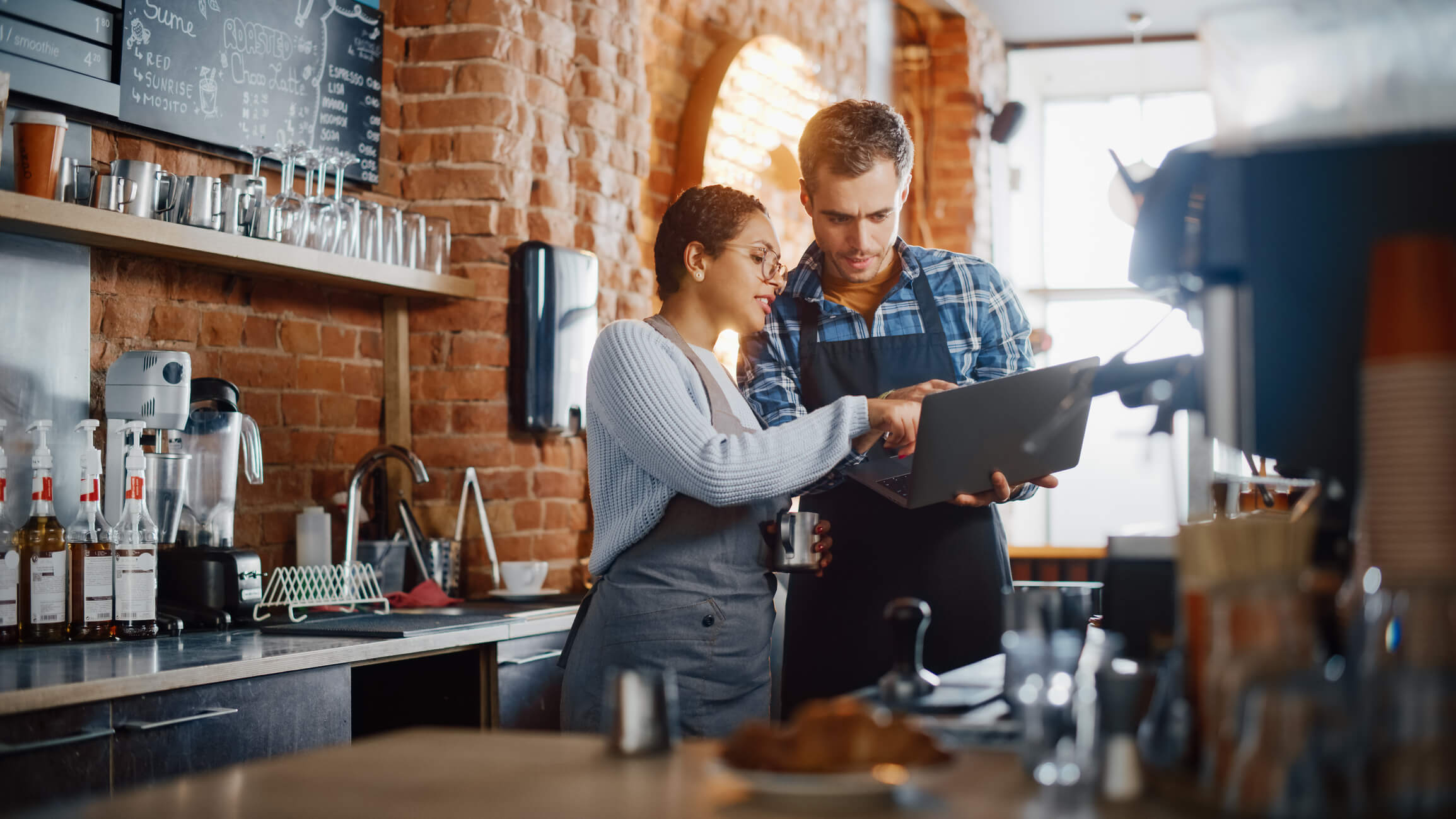 two entrepreneurs looking at a laptop in a coffee shop