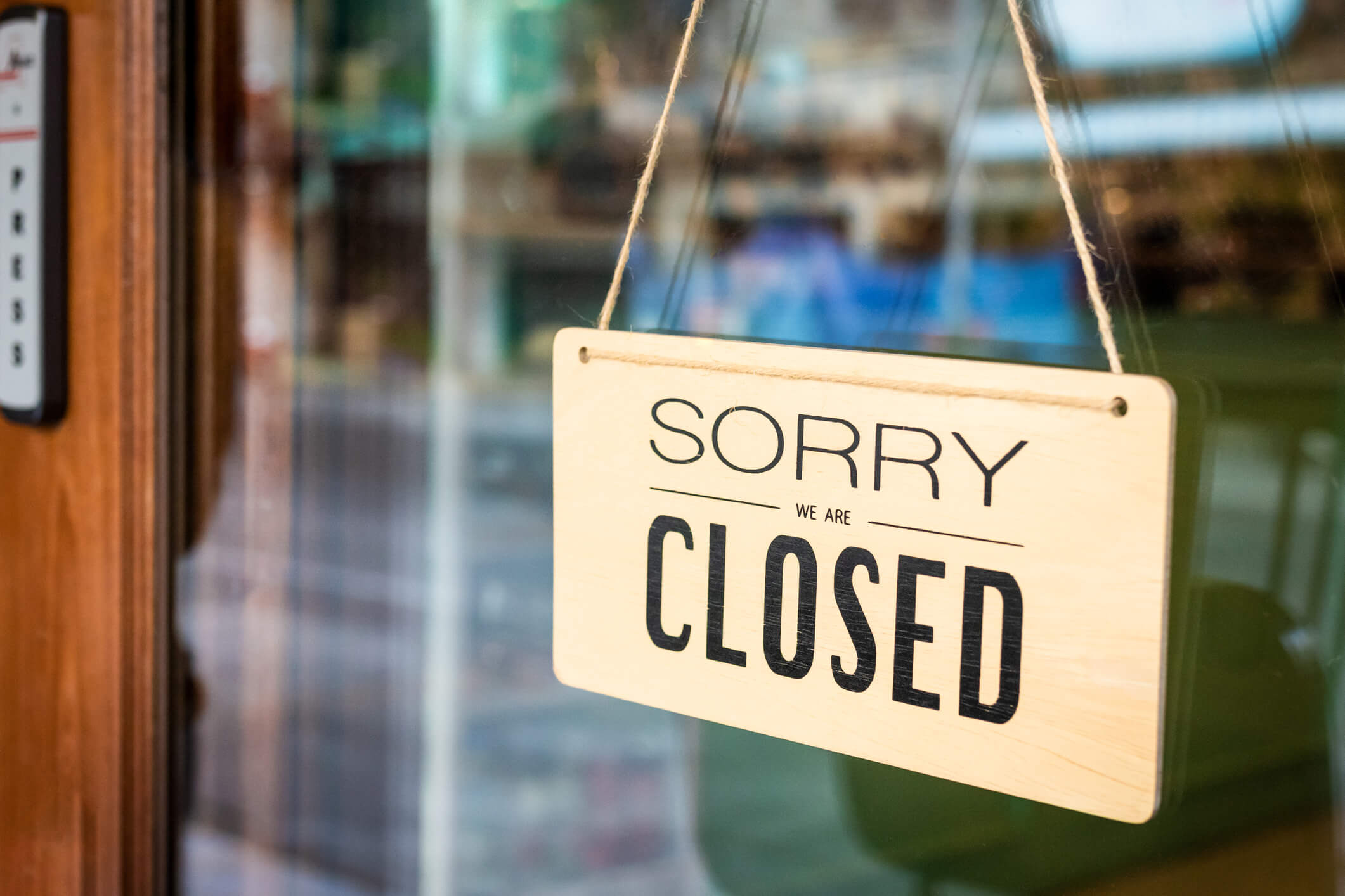sorry we are closed sign hanging on the door of a business