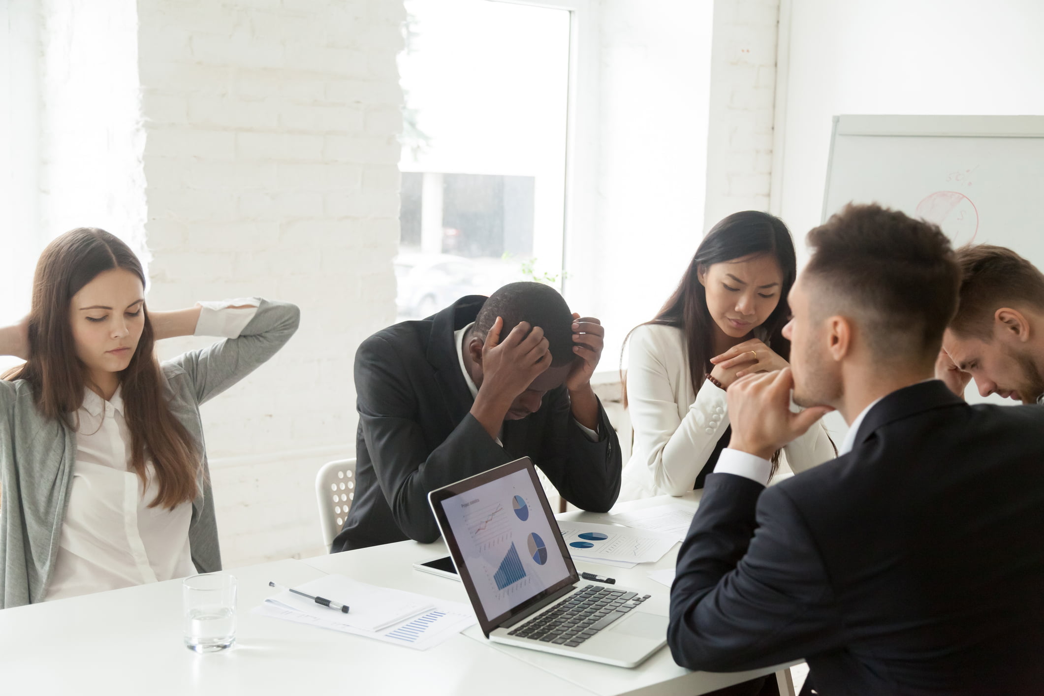 business people looking stressed crowded round a laptop