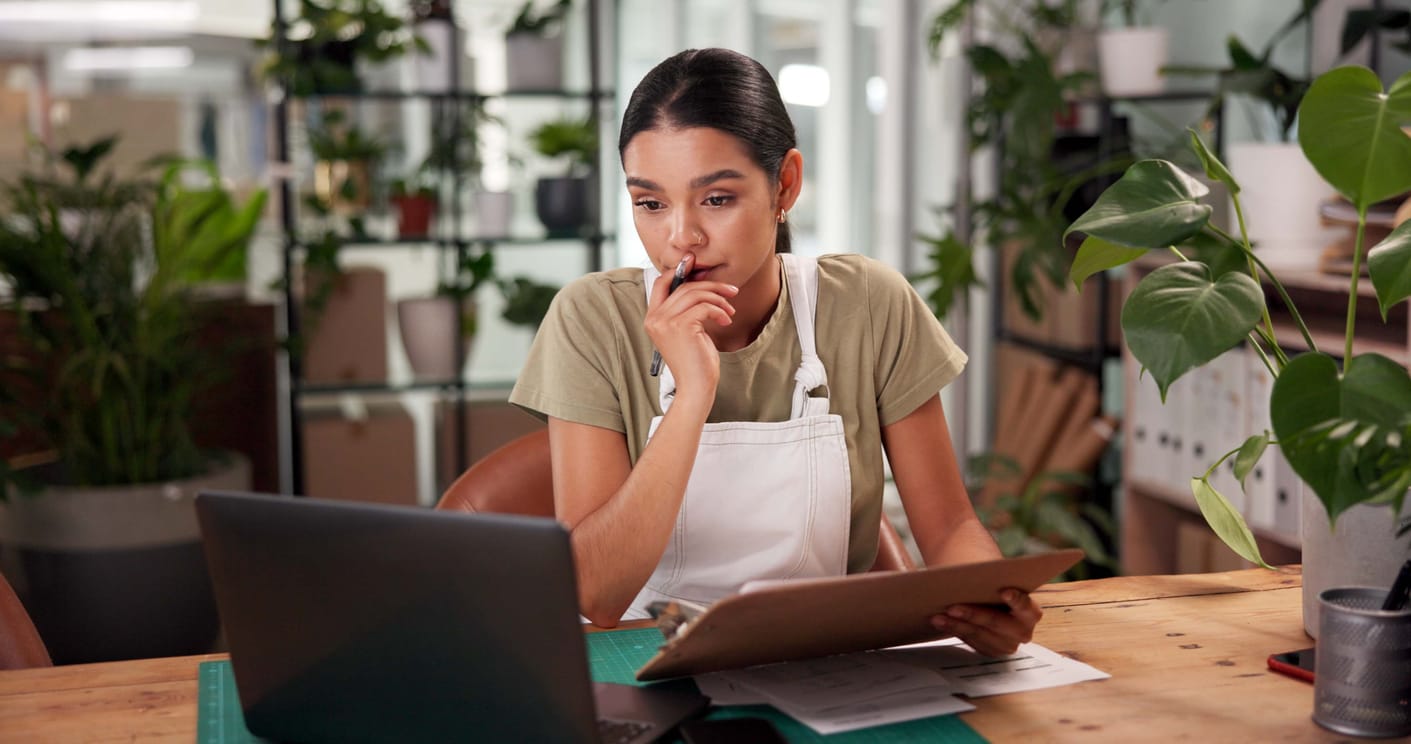 a small business owner at a house plant shop looking at her laptop