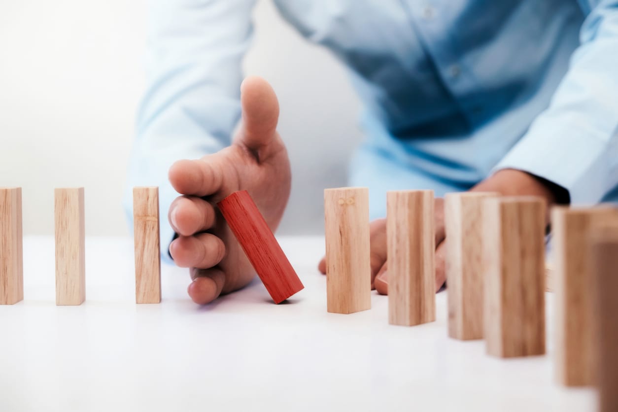 Businessman hand stop dominoes continuous toppled or risk